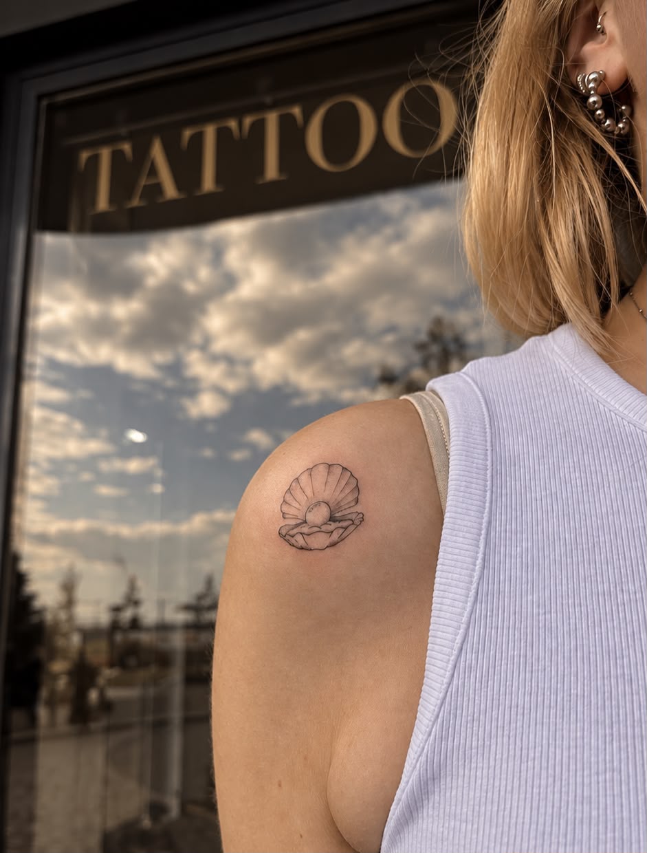 Fine-Line Muschel-Tattoo auf der Schulter