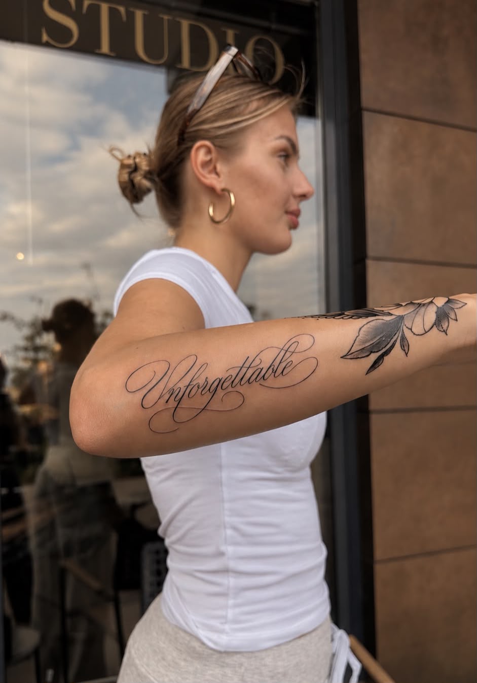 Schriftzug „Unforgettable“ mit floralem Motiv am Unterarm
